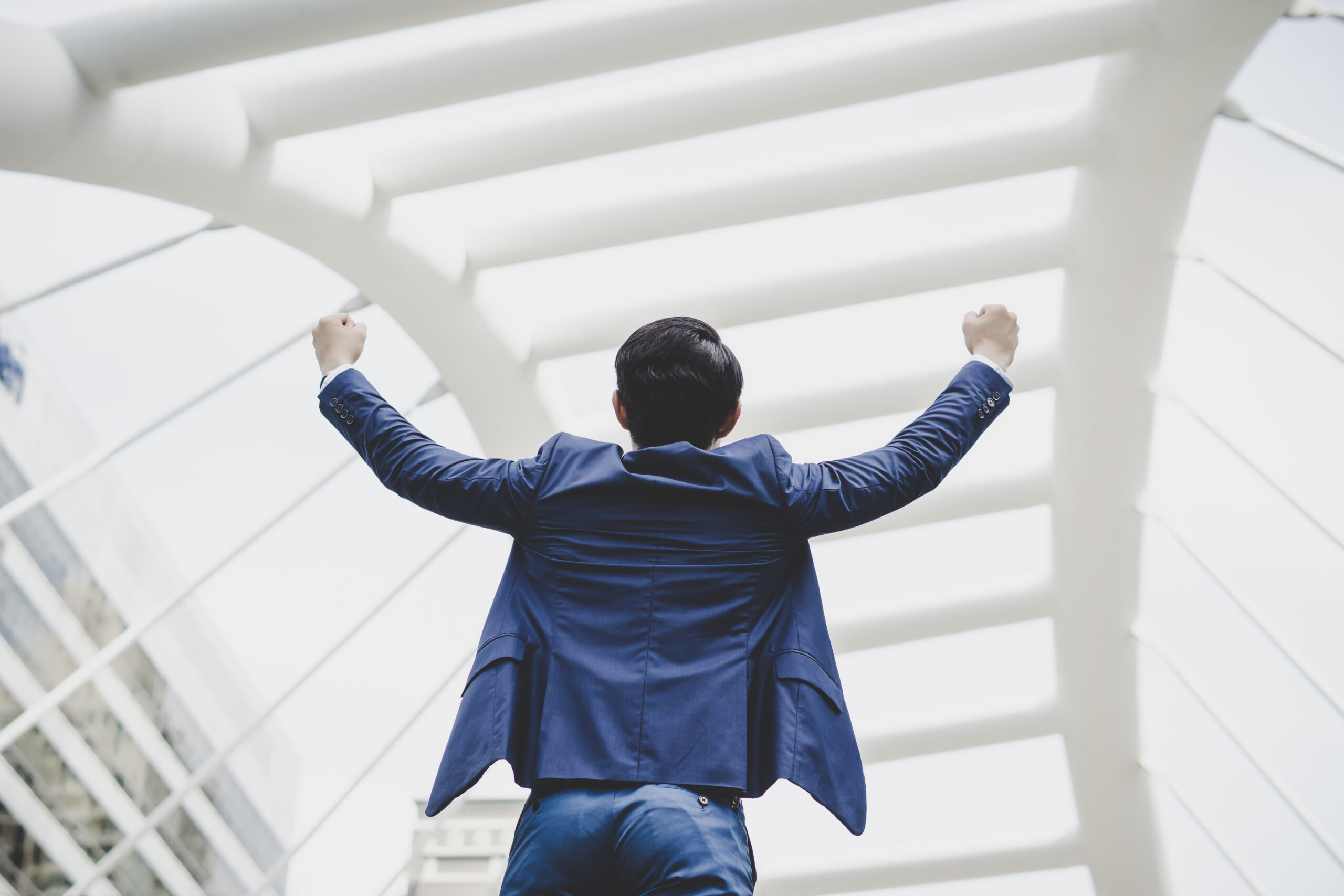 Successfully of young businessman keeping arms raised and expres